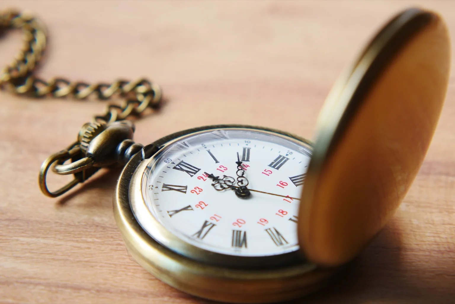 שעון כיס עתיק מפליז פתוח על משטח עץ — סמל להעברה בין דורית